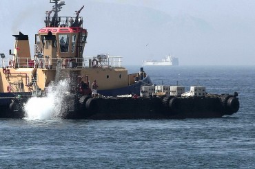 Workers throw concrete blocks from a Gibraltar tug to extend Gibraltar's artificial reef, on July 25, 2013 © A. Carrasco Ragel / EPA