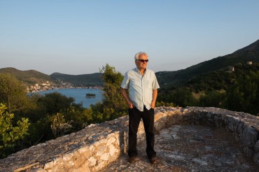 Former mayor of Ithaca, Spyros Arsenis stands on top of a watchtower with, behind him, a breathtaking view on Vathy and its bay © Philippe Henry / OCEAN71 Magazine